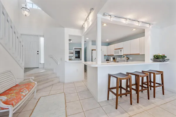 a kitchen with white cabinets and chairs