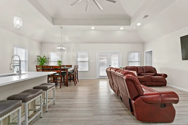 a kitchen with stainless steel appliances a microwave a stove a sink dishwasher a refrigerator and white cabinets with wooden floor