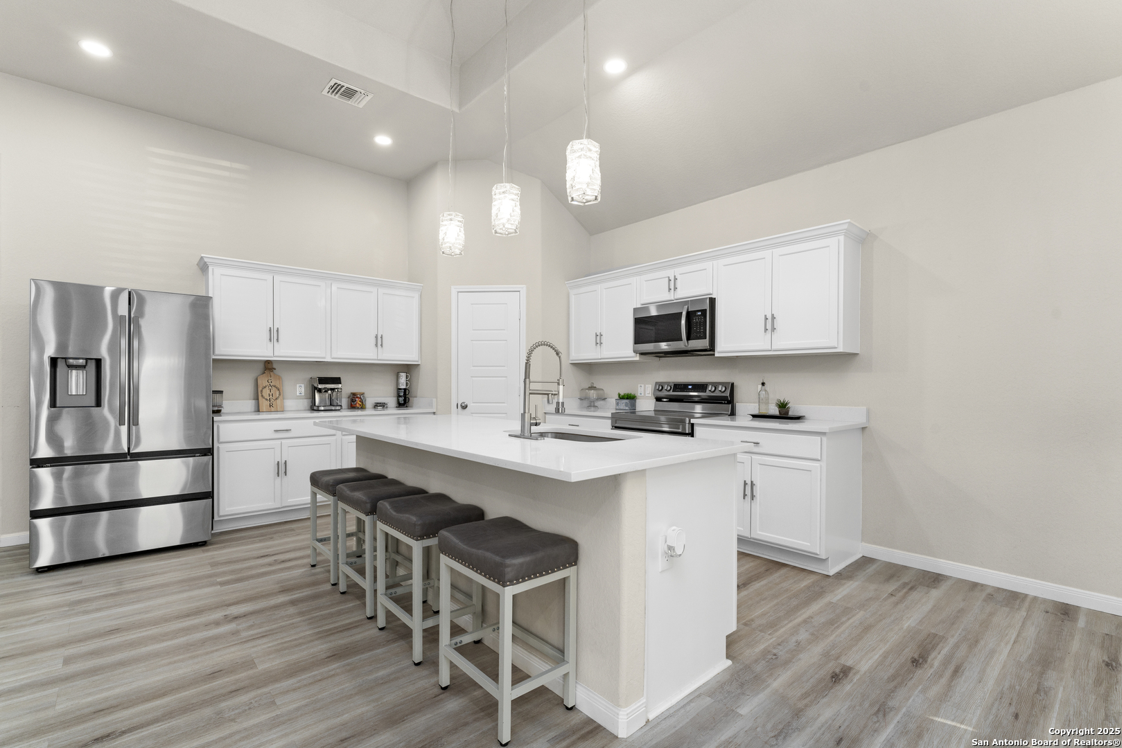 16851 Griffin Road, Unit 2 Atascosa, TX 78002 - Photo 17 of 37 a kitchen with stainless steel appliances a microwave a stove a sink dishwasher a refrigerator and white cabinets with wooden floor