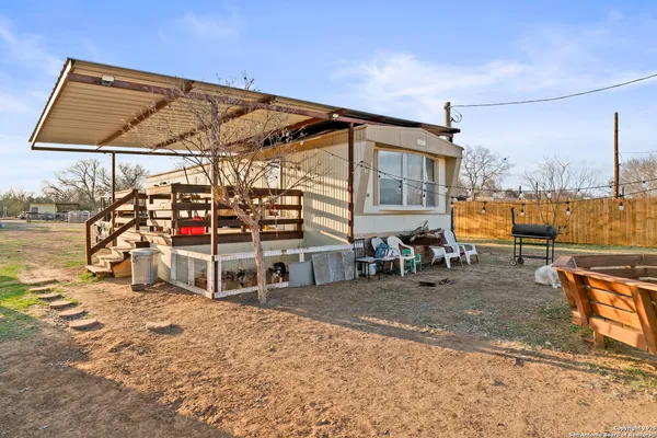 a backyard of a house with a large tree and wooden fence