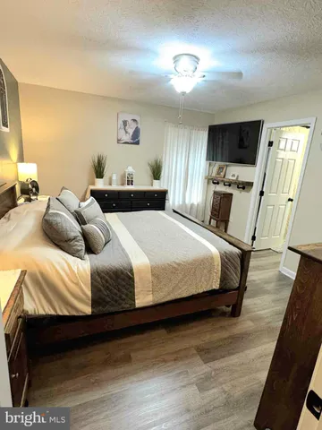 a bedroom with a bed a mirror on dresser and a table