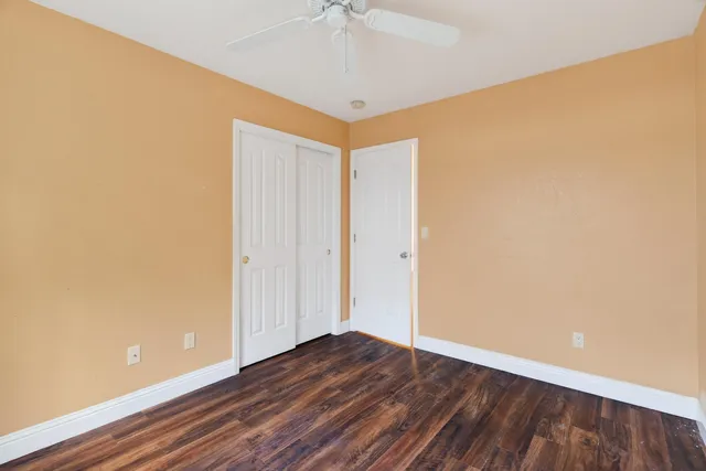 a view of a room with wooden floor and a ceiling fan
