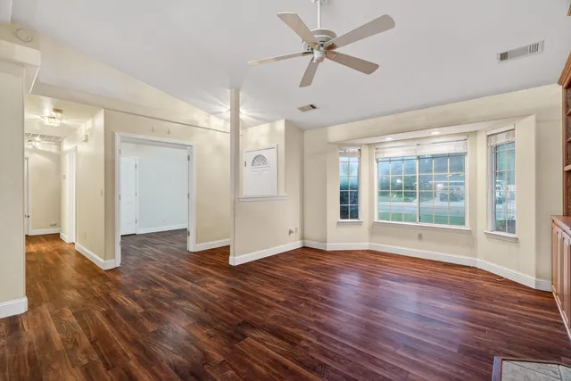 a view of empty room with wooden floor and fan