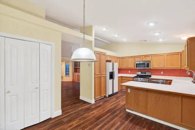 a kitchen with stainless steel appliances granite countertop a refrigerator a stove and a wooden floors