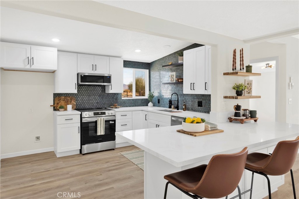 14344 Central Road Apple Valley, CA 92307 - Photo 11 of 61 a kitchen with stainless steel appliances a stove a sink dishwasher a refrigerator and a dining table with wooden floor