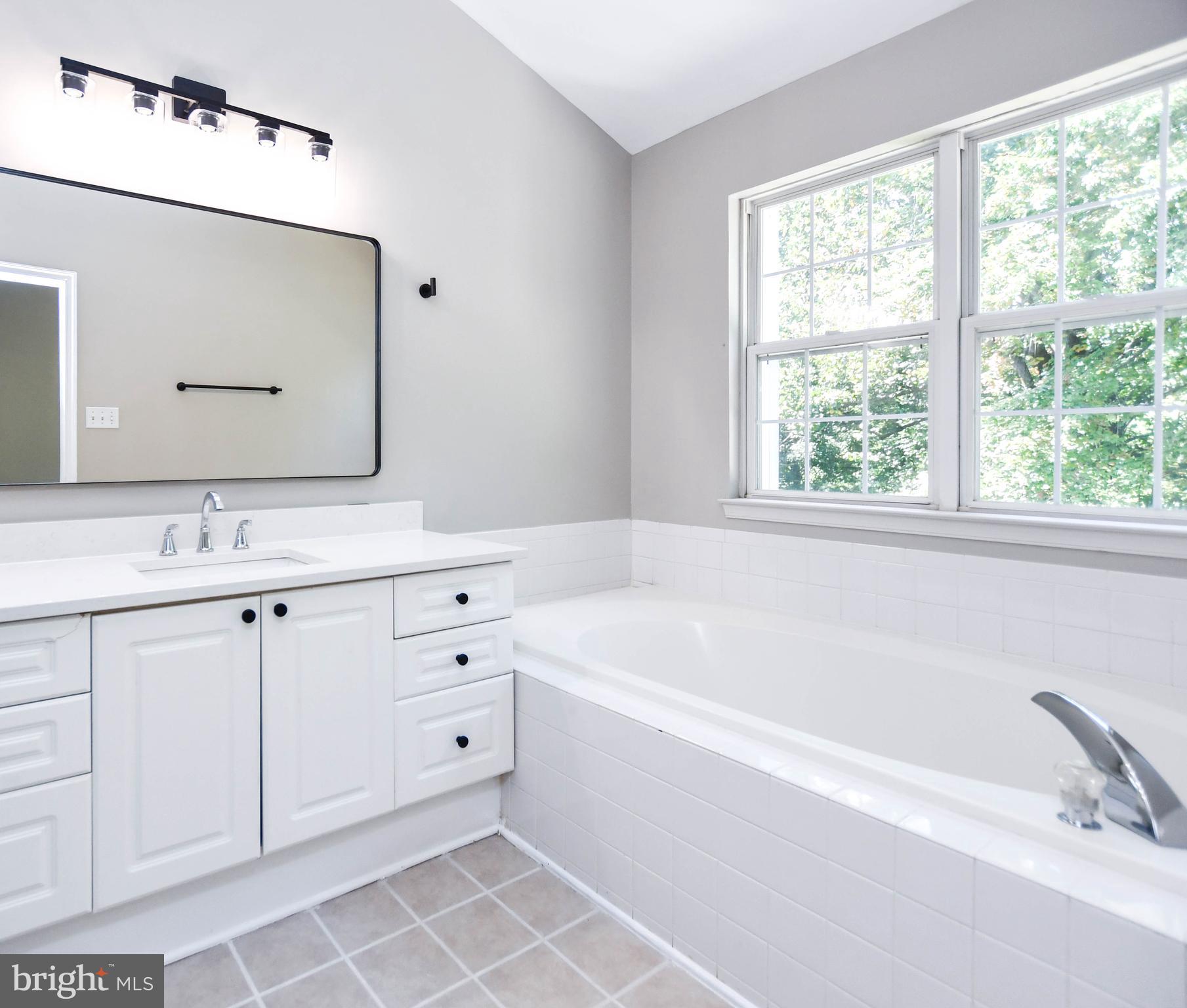 4308 Huntshire Road Randallstown, MD 21133 - Photo 26 of 40 a bathroom with a double vanity sink large mirror and a bathtub