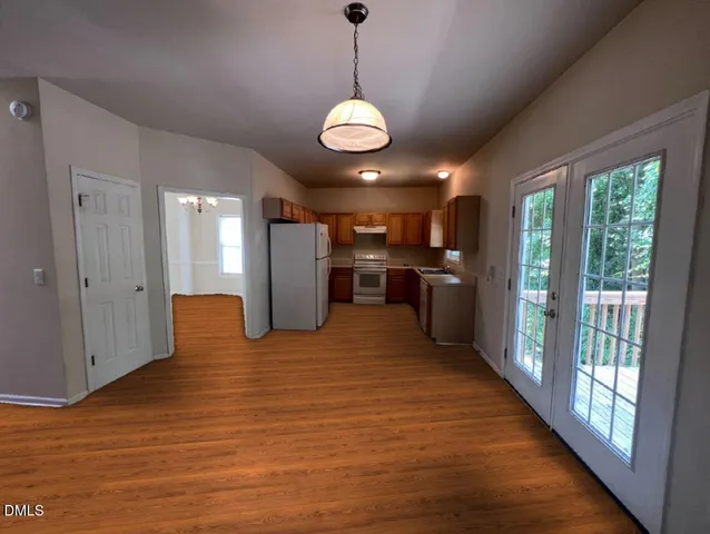 a view of a kitchen with a refrigerator wooden floor and windows