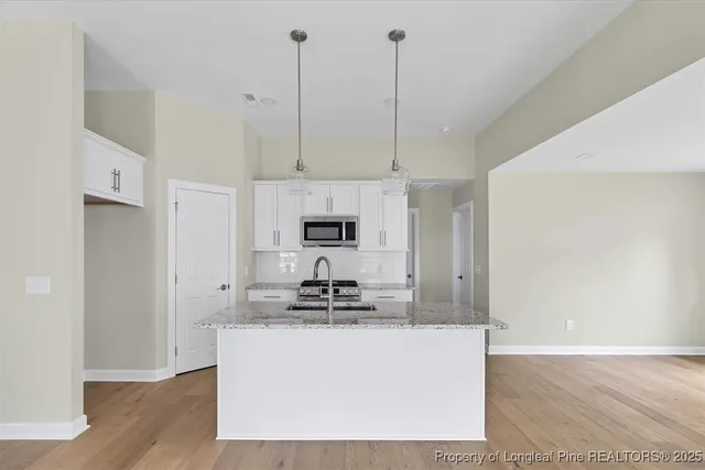 a kitchen with kitchen island stainless steel appliances a sink a refrigerator a stove a microwave and cabinets