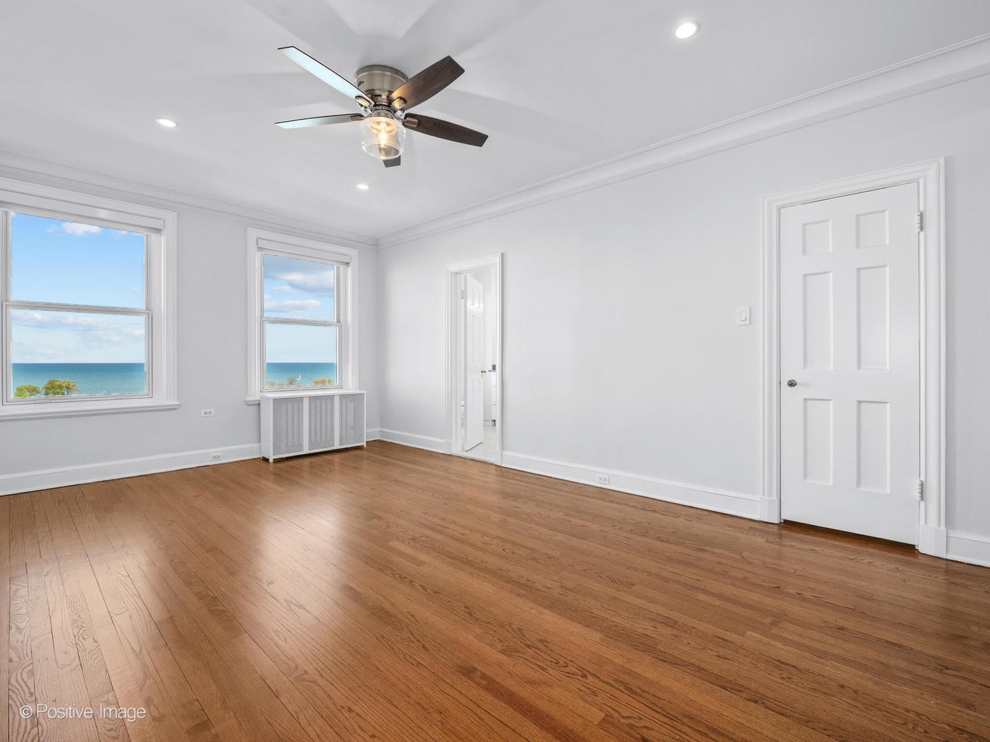 3240 North Lake Shore Drive, Unit 11B Chicago, IL 60657 - Photo 14 of 25 an empty room with wooden floor chandelier fan and windows