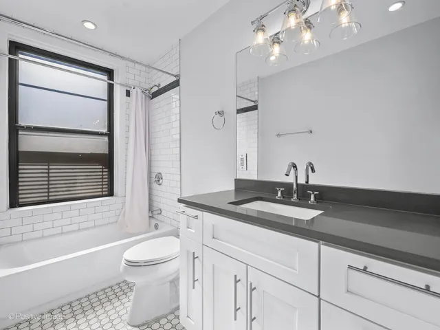 a bathroom with a granite countertop sink a toilet a mirror and bathtub