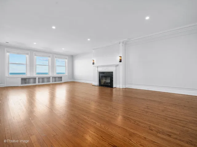 an empty room with wooden floor and a fireplace