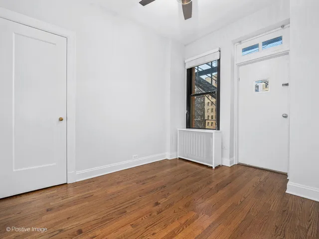 an empty room with wooden floor cabinet and windows