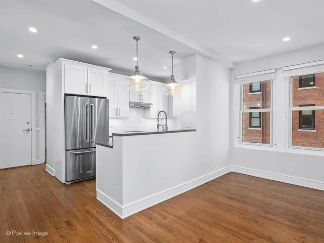 a kitchen with kitchen island a counter top space wooden floor and stainless steel appliances