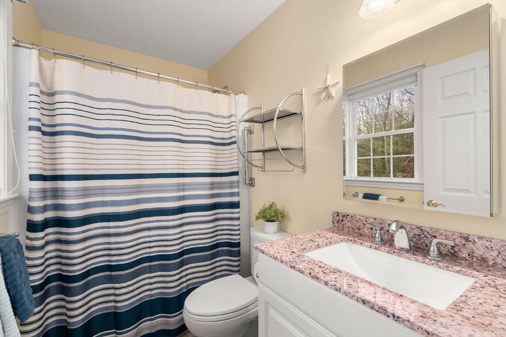 42 Brewster Road, Unit 42 Stoughton, MA 02072 - Photo 9 of 29 a bathroom with a granite countertop sink a toilet a mirror and shower curtain