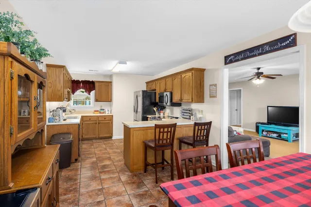 a kitchen with a refrigerator a stove top oven a sink dishwasher and wooden cabinets with wooden floor