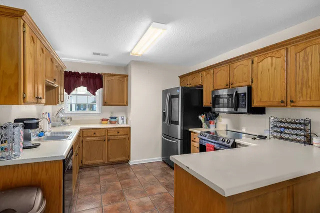 a kitchen with stainless steel appliances granite countertop a stove top oven a sink a dining table and chairs with wooden floor