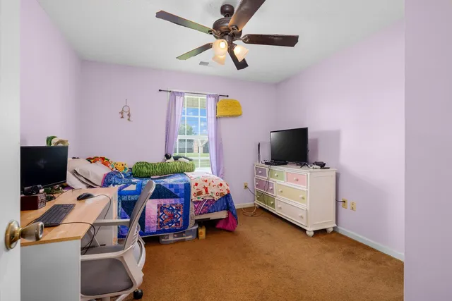 a view of a bedroom with workspace and windows