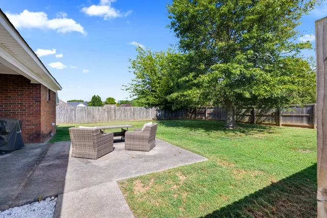 a view of a patio with table and chairs potted plants and a large tree