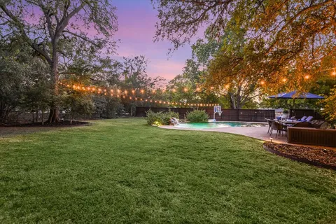 a view of a backyard with table and chairs under a large tree