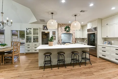 a kitchen with stainless steel appliances a dining table chairs stove and sink