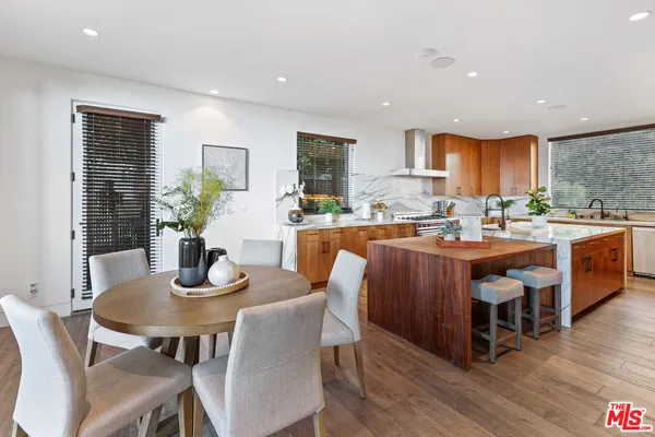 a dining room with stainless steel appliances kitchen island granite countertop a dining table chairs and a refrigerator