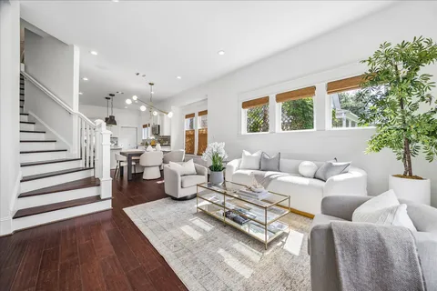 a kitchen with stainless steel appliances a stove a refrigerator a sink a stove and white cabinets with wooden floor