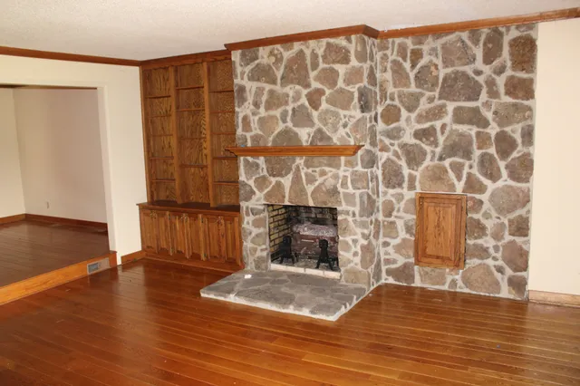 an empty room with wooden floor and a fireplace