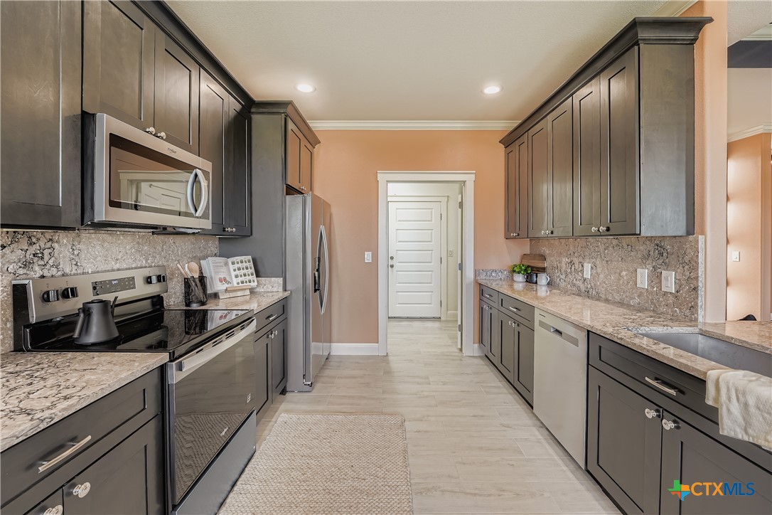 222 Arosa Drive Elgin, TX 78621 - Photo 13 of 40 a large kitchen with stainless steel appliances granite countertop wooden cabinets a stove top oven a sink and dishwasher