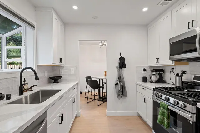 a kitchen with refrigerator a sink a stove and cabinets