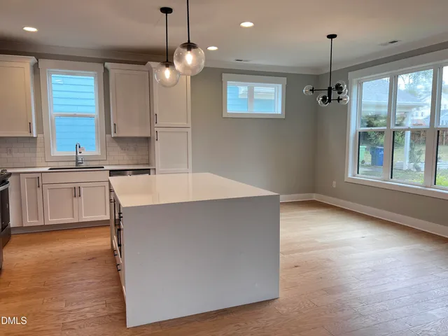a kitchen with kitchen island a counter top a stove a sink a window and cabinets