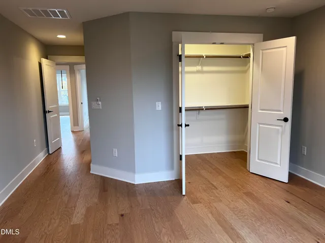 an empty room with wooden floor and entrance