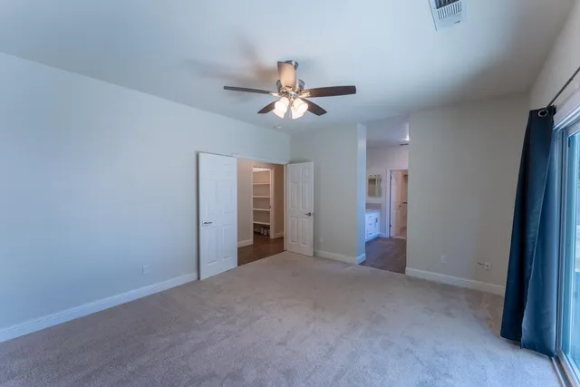 an empty room with closet and a ceiling fan