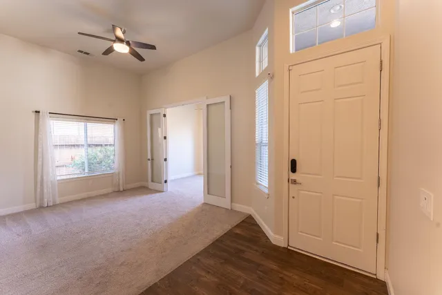 a view of empty room with wooden floor and fan