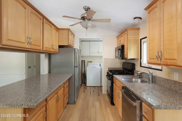 a kitchen with granite countertop a sink a counter space appliances and cabinets