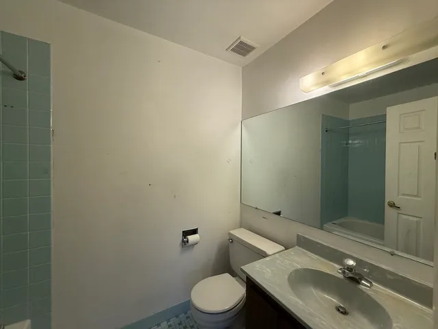 a bathroom with a granite countertop sink toilet and a mirror