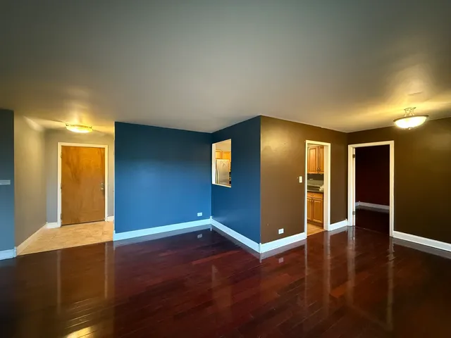 a view of an empty room with wooden floor and closet
