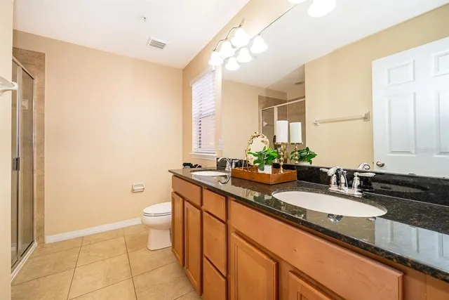 a bathroom with a granite countertop sink toilet and mirror