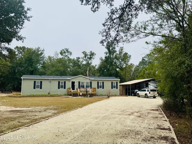 a view of house with outdoor seating and covered with trees