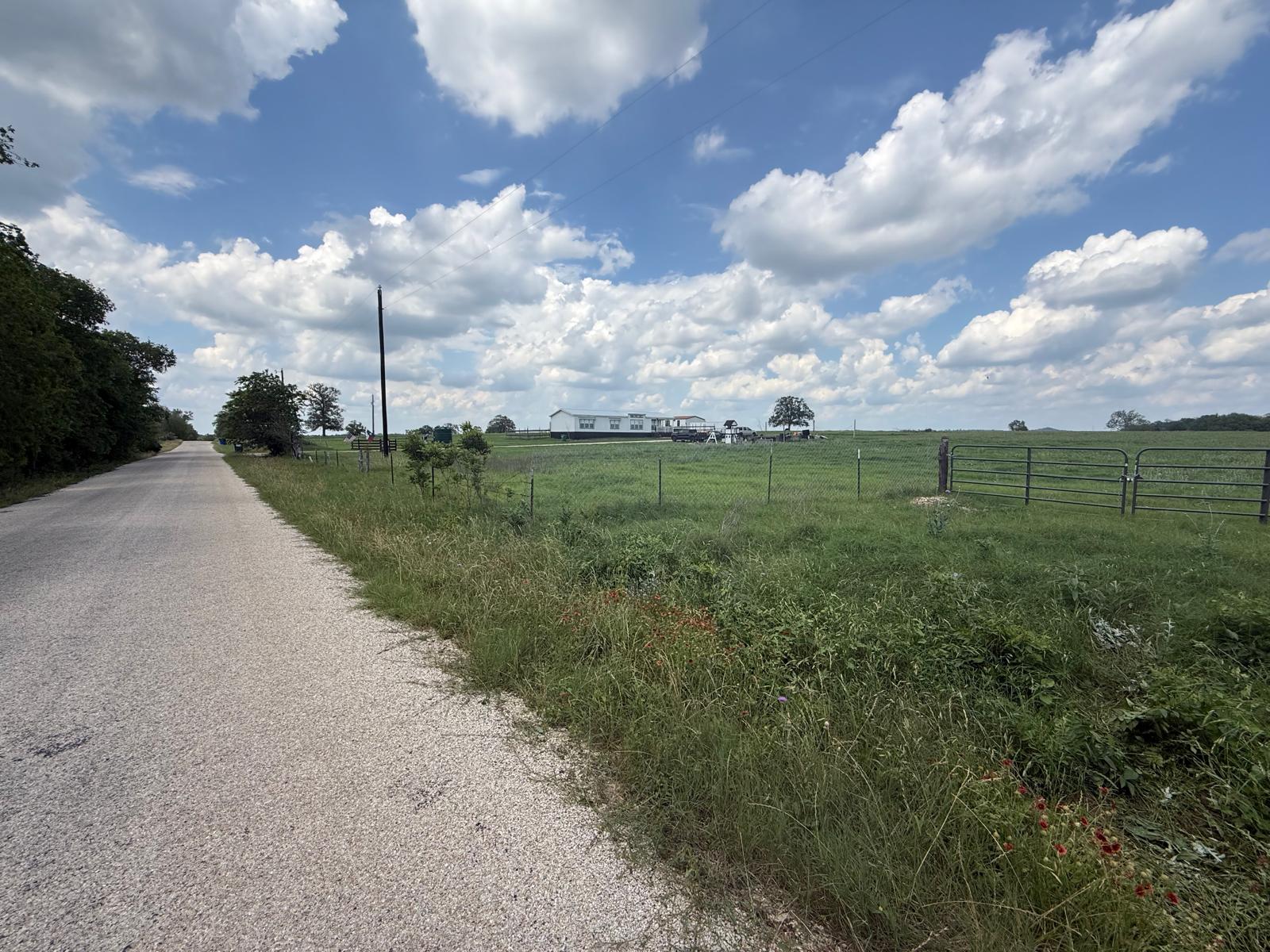 5309 Tenney Creek Road Luling, TX 78648 - Photo 9 of 10 A private gravel road leads to a serene rural landscape, showcasing the expansive green fields.