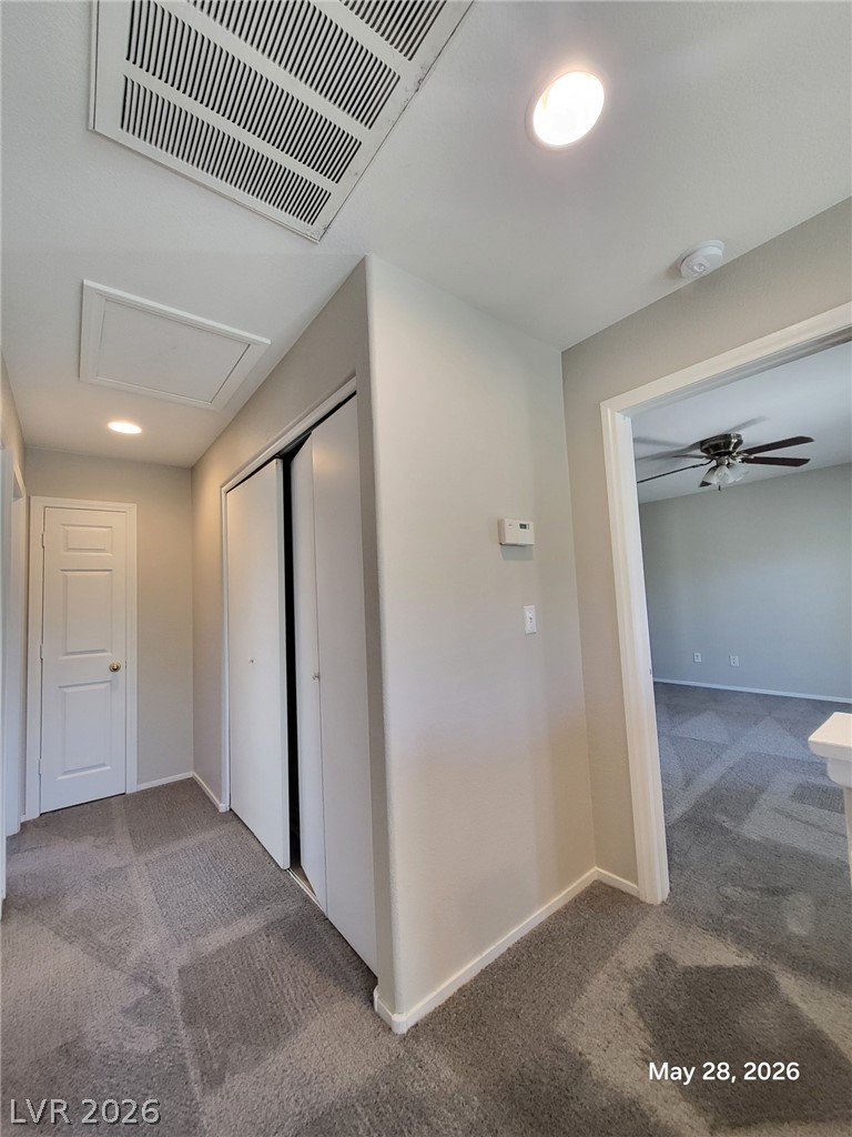 9843 West Overlook Ridge Avenue Las Vegas, NV 89148 - Photo 10 of 19 A quiet hall with plush gray carpeting and a closet, offering a glimpse into an adjoining room with a ceiling fan.