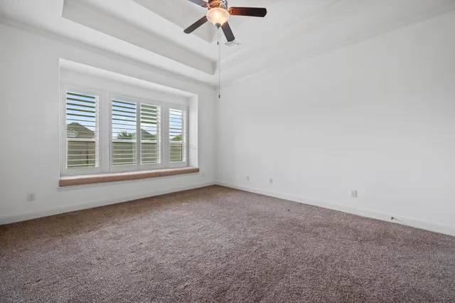 an empty room with a ceiling fan and window