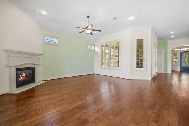 a view of an empty room with wooden floor fireplace and a window