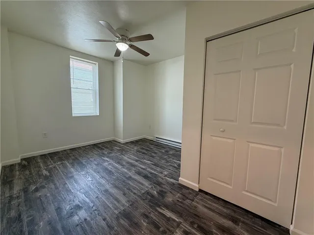 an empty room with wooden floor closet and windows