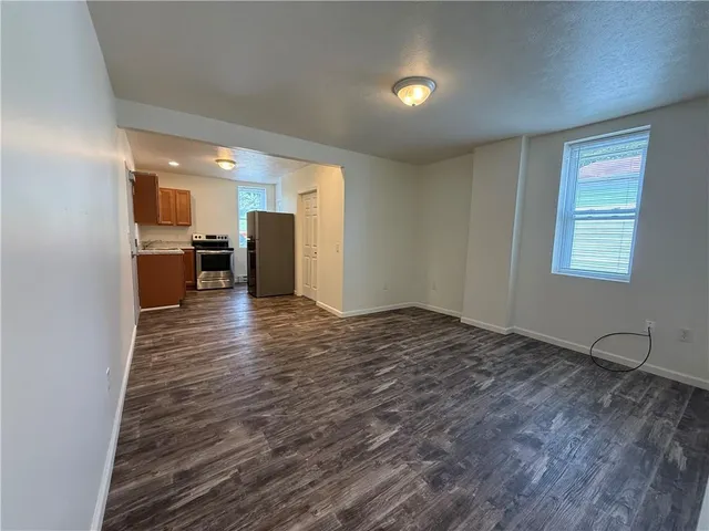 a view of empty room with kitchen and window
