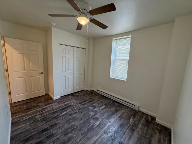 an empty room with wooden floor closet and windows