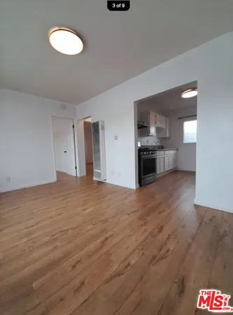 a big room with wooden floor and kitchen view