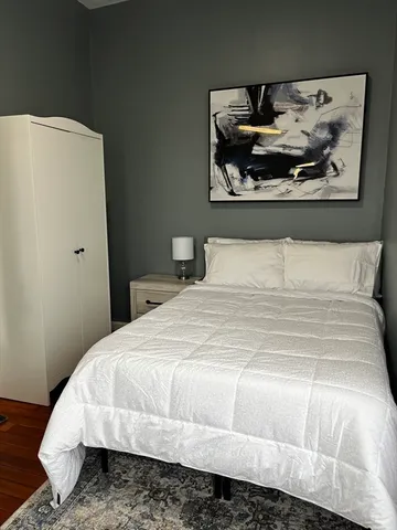a bedroom with a bed and painting on the wall