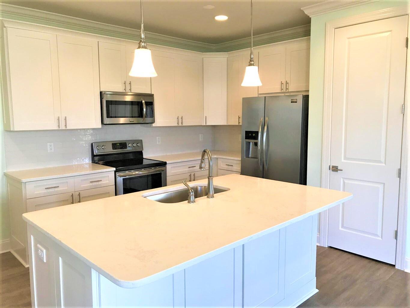 148 Chapman Street Santa Rosa Beach, FL 32459 - Photo 5 of 23 a kitchen with stainless steel appliances granite countertop a sink a stove a refrigerator a microwave with white cabinets and wooden floor