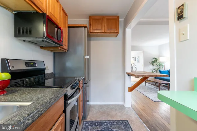 a kitchen with stainless steel appliances granite countertop a sink a stove and a wooden cabinets