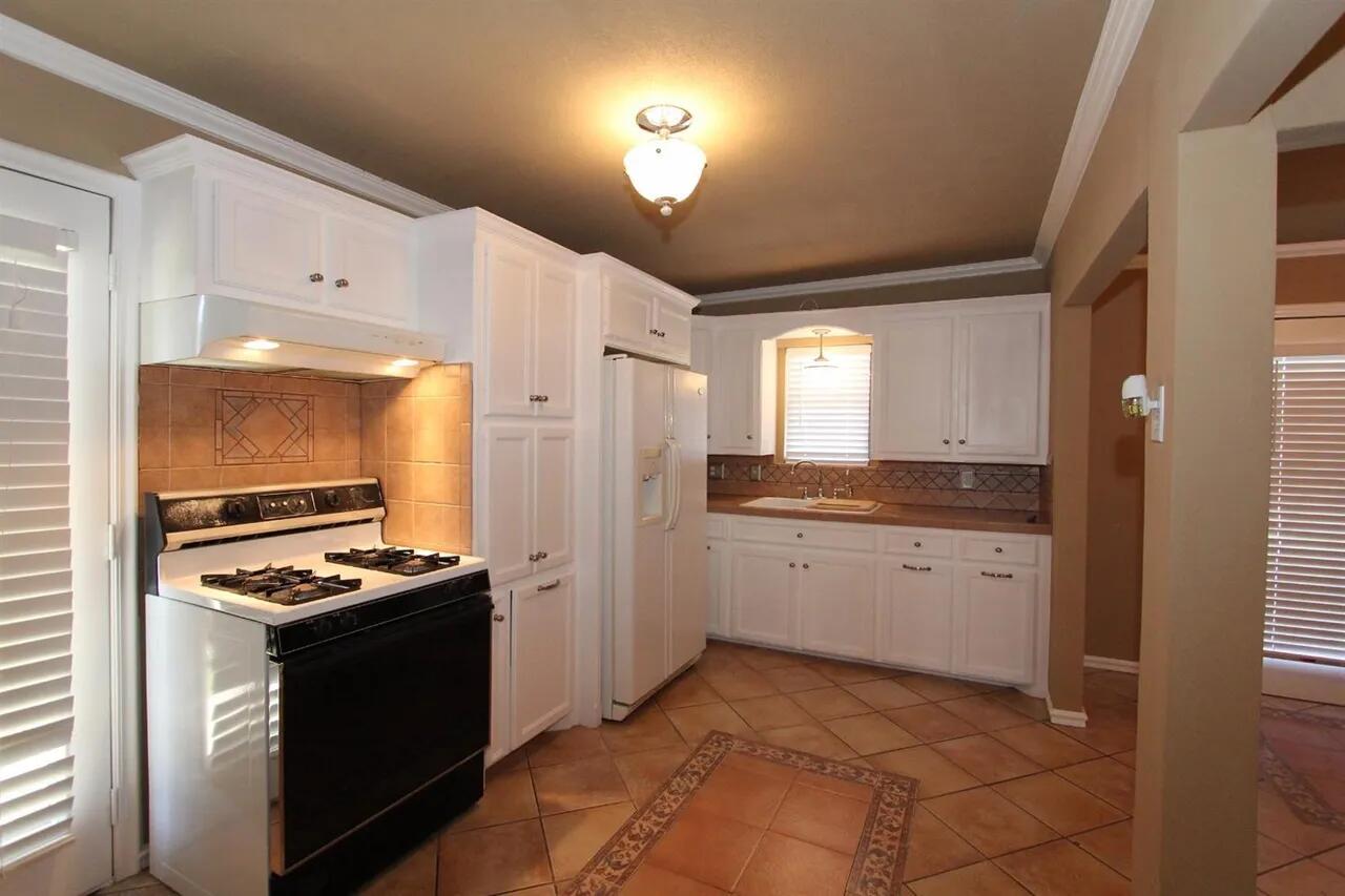 2610 35th Street Lubbock, TX 79410 - Photo 6 of 19 a kitchen with granite countertop a stove and a refrigerator
